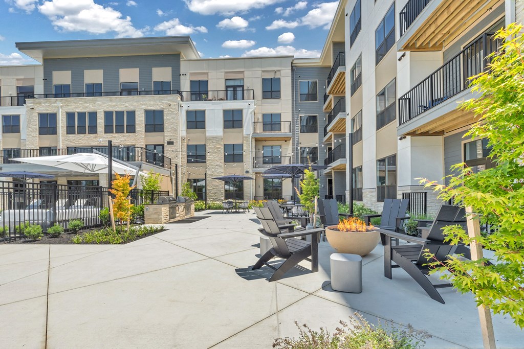 A patio area with chairs and a fire pit in front of apartment buildings at Luxe 360 on Centerpointe Apartments, Virginia, 23114