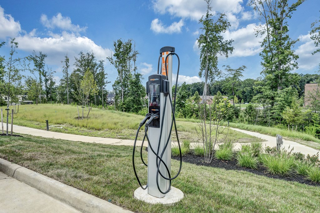 An electric vehicle charging station is on a concrete pad in a grassy area.
