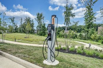 An electric vehicle charging station is on a concrete pad in a grassy area