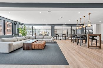 A modern living room with a grey sofa, a wooden coffee table, and a black rug at Luxe 360 on Centerpointe Apartments, Midlothian, VA