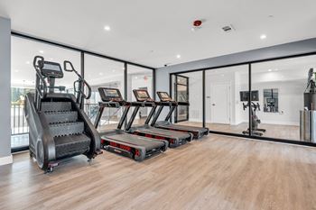 A gym with treadmills, elliptical machines, and a stair climber at Luxe 360 on Centerpointe Apartments, Midlothian, VA, 23114