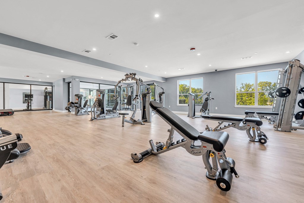 A gym with a variety of equipment including a bench press at Luxe 360 on Centerpointe Apartments, Midlothian, VA, 23114