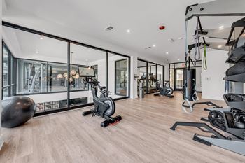 A gym with a variety of equipment including a stationary bike, a treadmill, and a rowing machine at Luxe 360 on Centerpointe Apartments, Midlothian, VA