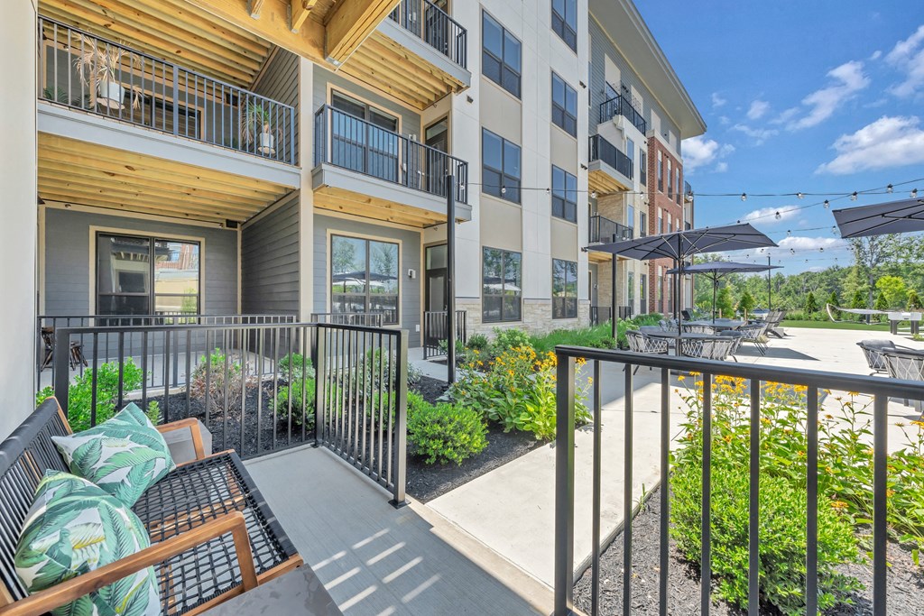 A balcony with a table and chairs overlooks a courtyard at Luxe 360 on Centerpointe Apartments, Midlothian, VA, 23114