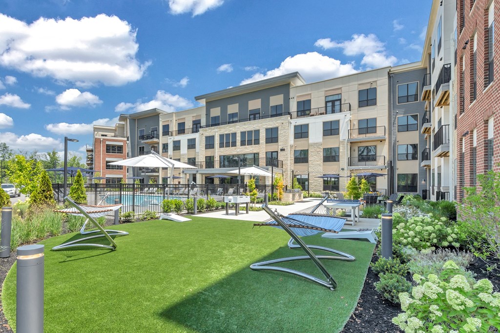 A sunny day at a modern apartment complex with a green lawn and a pool at Luxe 360 on Centerpointe Apartments, Virginia