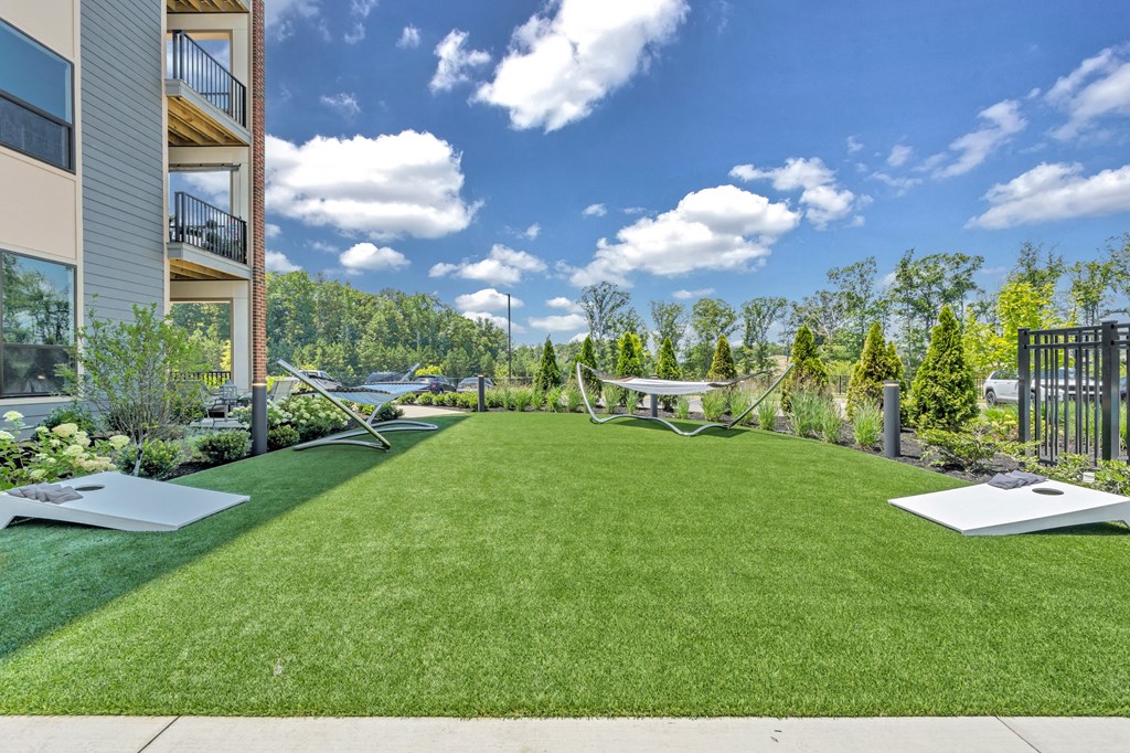 A large grassy area in front of a building with a white lawn chair and a black metal fence at Luxe 360 on Centerpointe Apartments, Midlothian, 23114