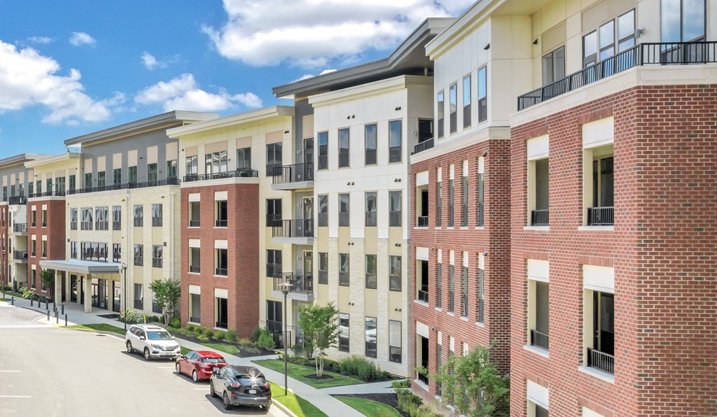 A row of red brick apartment buildings with cars parked in front at Luxe 360 on Centerpointe Apartments, Midlothian, Virginia