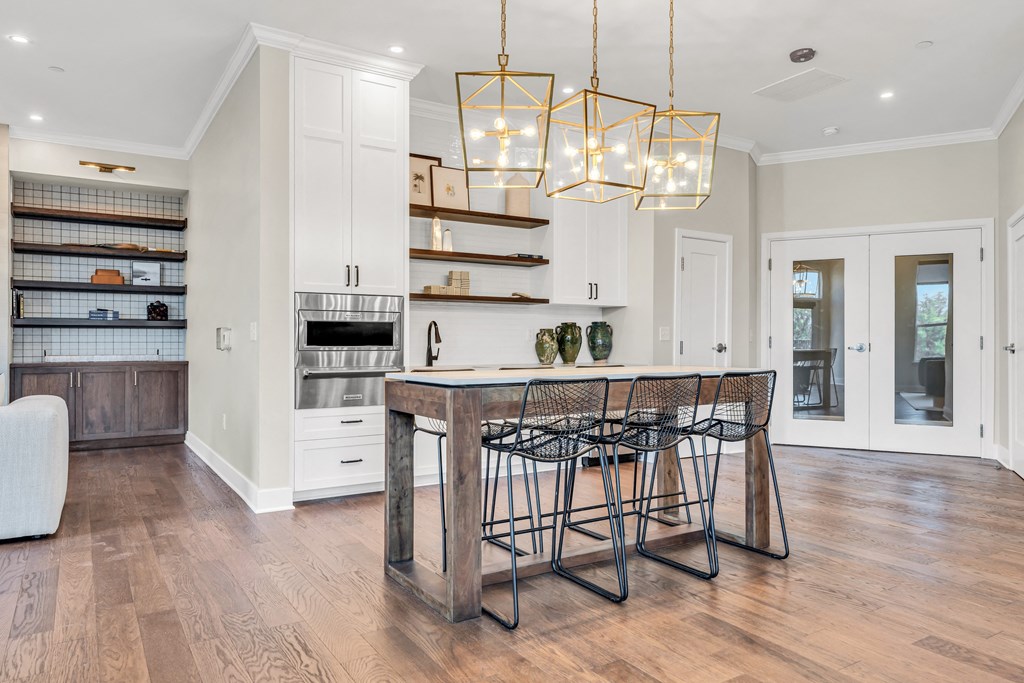 A kitchen with a wooden table and chairs and a hanging light fixture at Luxe 360 on Centerpointe Apartments, Midlothian