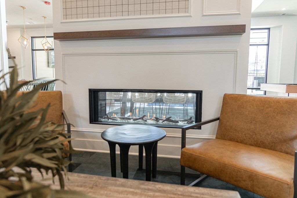 A living room with a fireplace and a brown leather chair at Luxe 360 on Centerpointe Apartments, Virginia