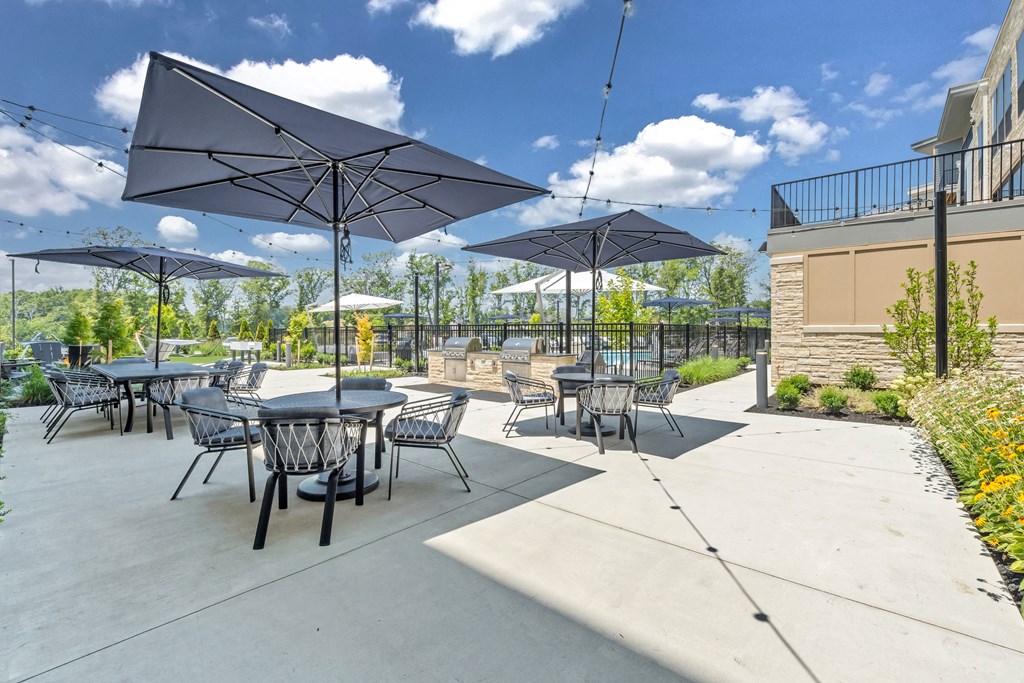 A patio with tables and chairs under umbrellas at Luxe 360 on Centerpointe Apartments, Midlothian, VA