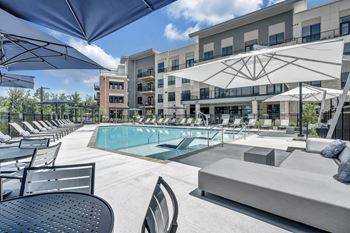 A pool area with a table and chairs and umbrellas