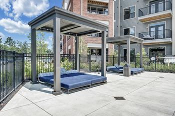 A concrete patio with a blue mattress and a black fence