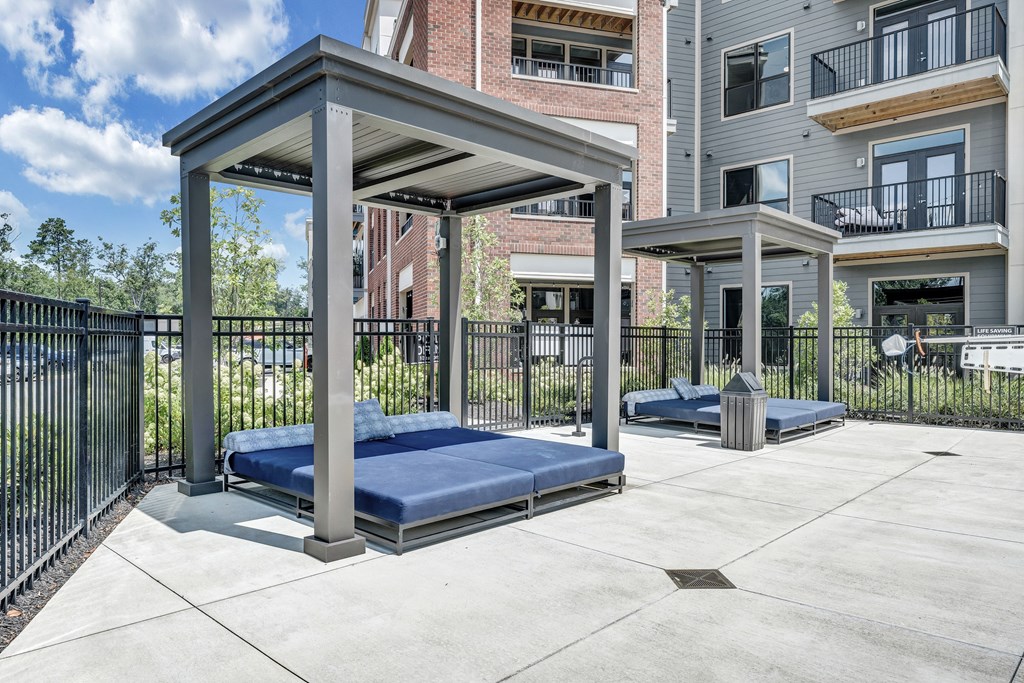 A concrete patio with a blue mattress and a black fence.