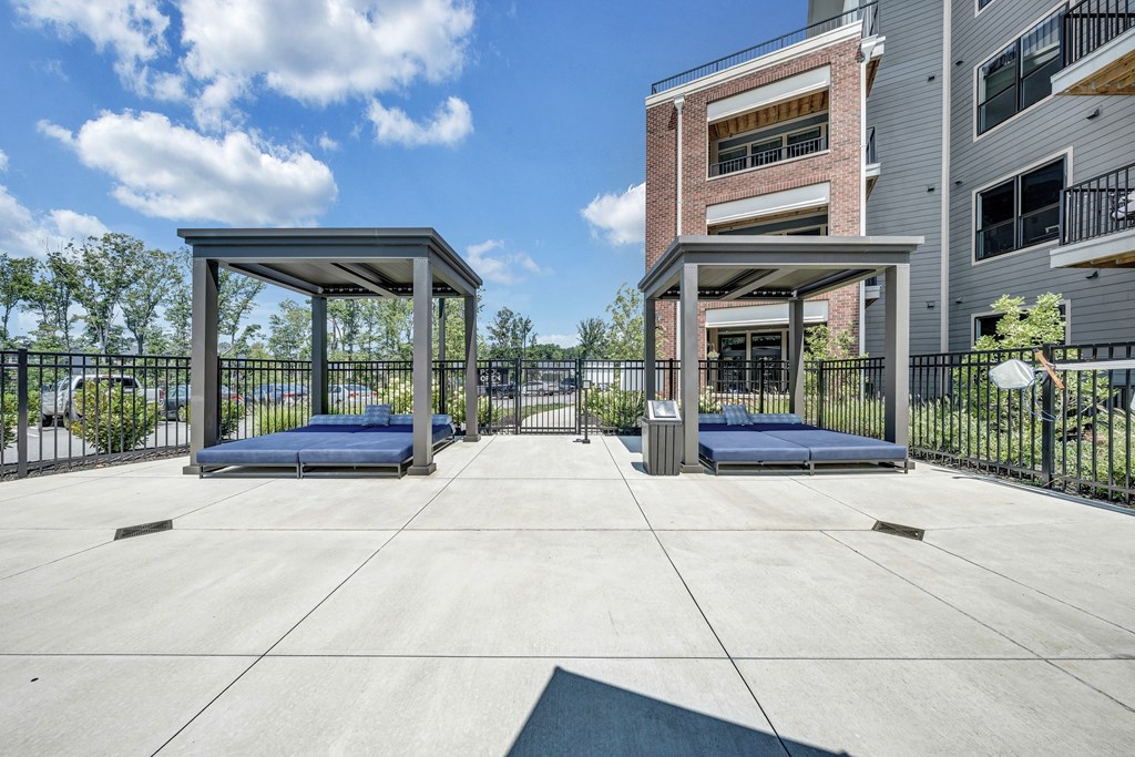 A concrete patio with two gazebos and a building in the background.