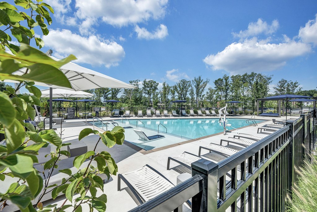 A pool area with sun shades and a metal fence.