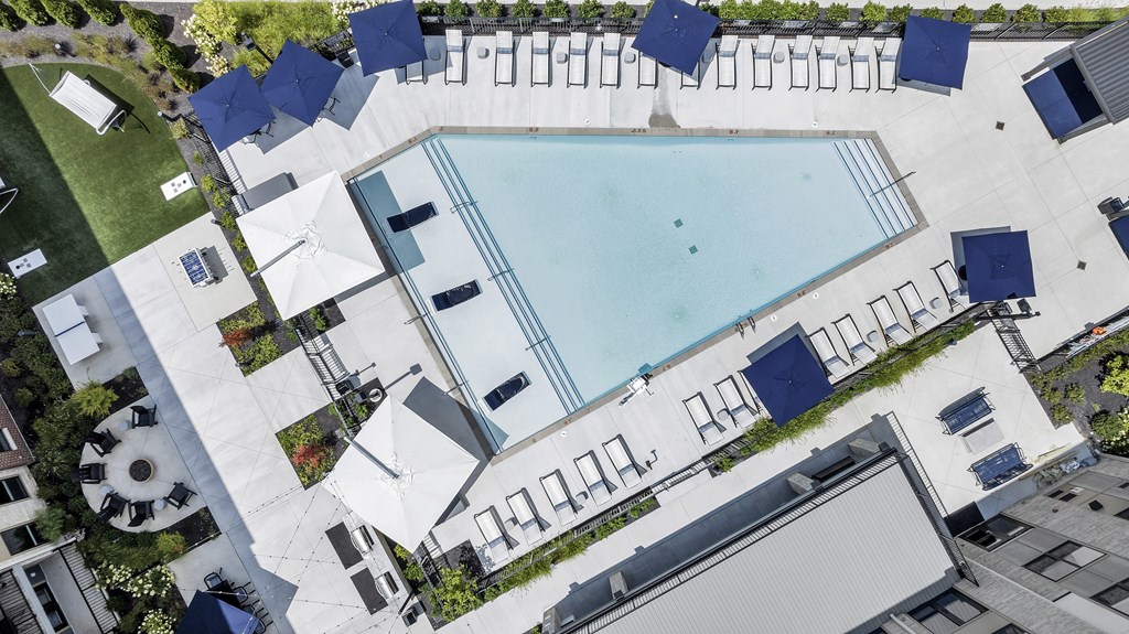 An aerial view of a pool surrounded by lounge chairs and umbrellas.
