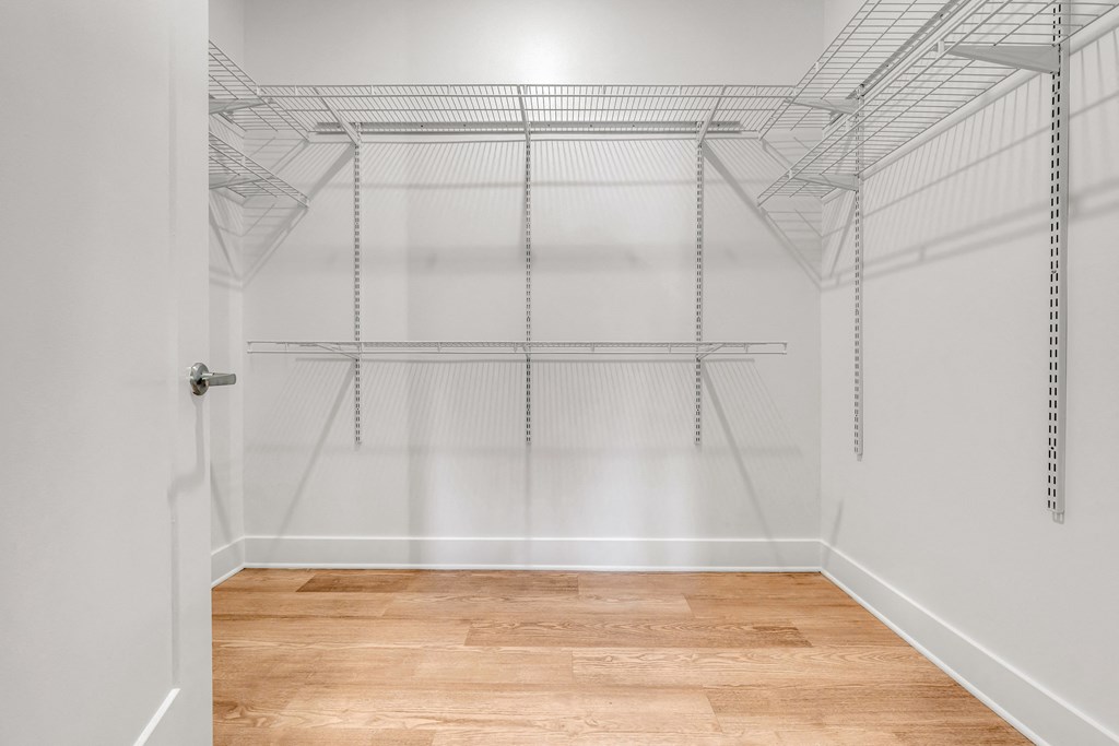 Empty walk-in closet with shelves and a wooden floor at Luxe 360 on Centerpointe Apartments, Midlothian, Virginia