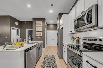 A modern kitchen with white appliances and a wooden floor at Luxe 360 on Centerpointe Apartments, Midlothian, Virginia