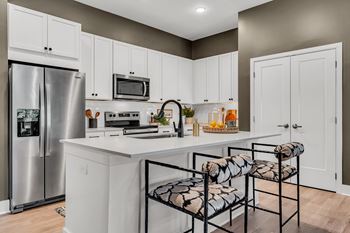 A kitchen with white cabinets and a stainless steel refrigerator at Luxe 360 on Centerpointe Apartments, Midlothian, VA