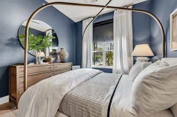 A bed with a canopy and a white bedspread in a room with blue walls at Luxe 360 on Centerpointe Apartments, Midlothian