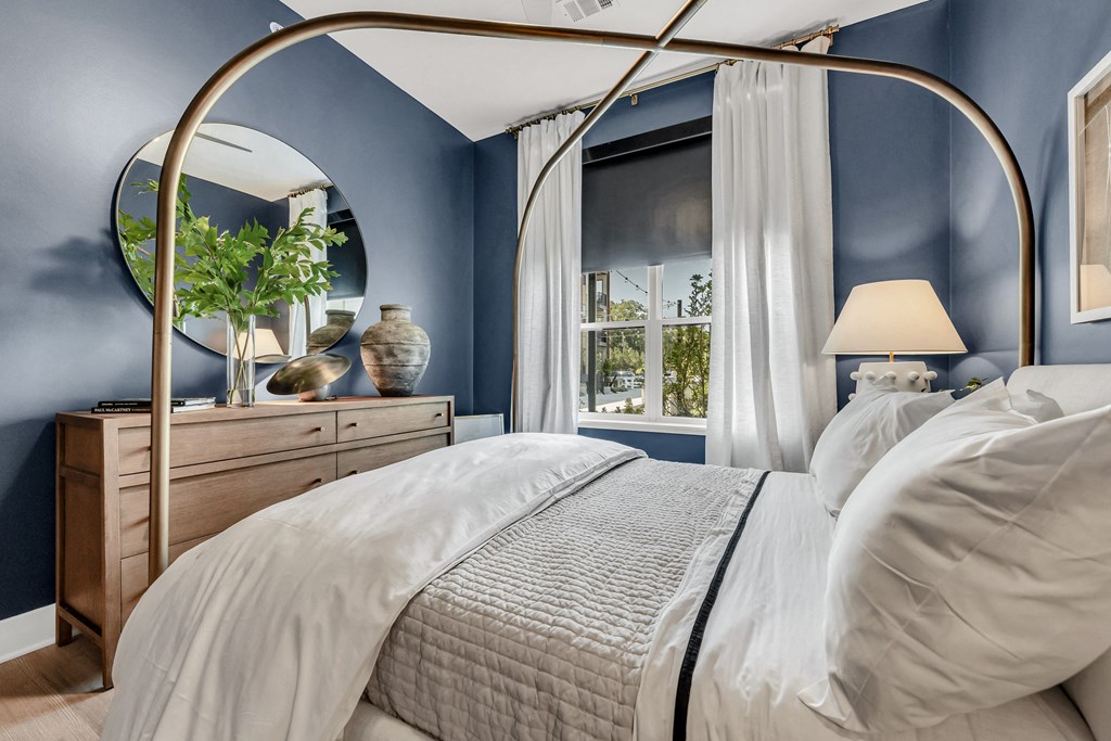 A bed with a canopy and a white bedspread in a room with blue walls at Luxe 360 on Centerpointe Apartments, Virginia