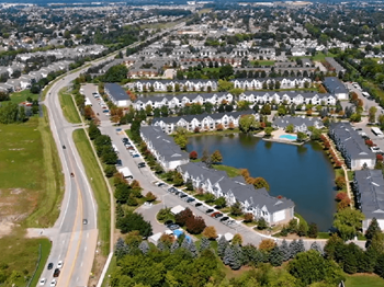 an aerial view of a subdivision with a lake and cars parked on the side of the road  at Northport Apartments, Michigan