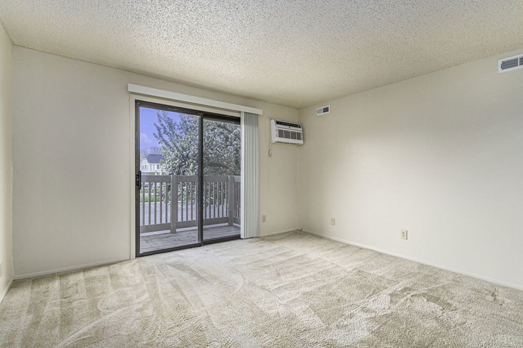 an empty living room with a sliding glass door to a balcony at Madeira Apartments, Kalamazoo, 49001