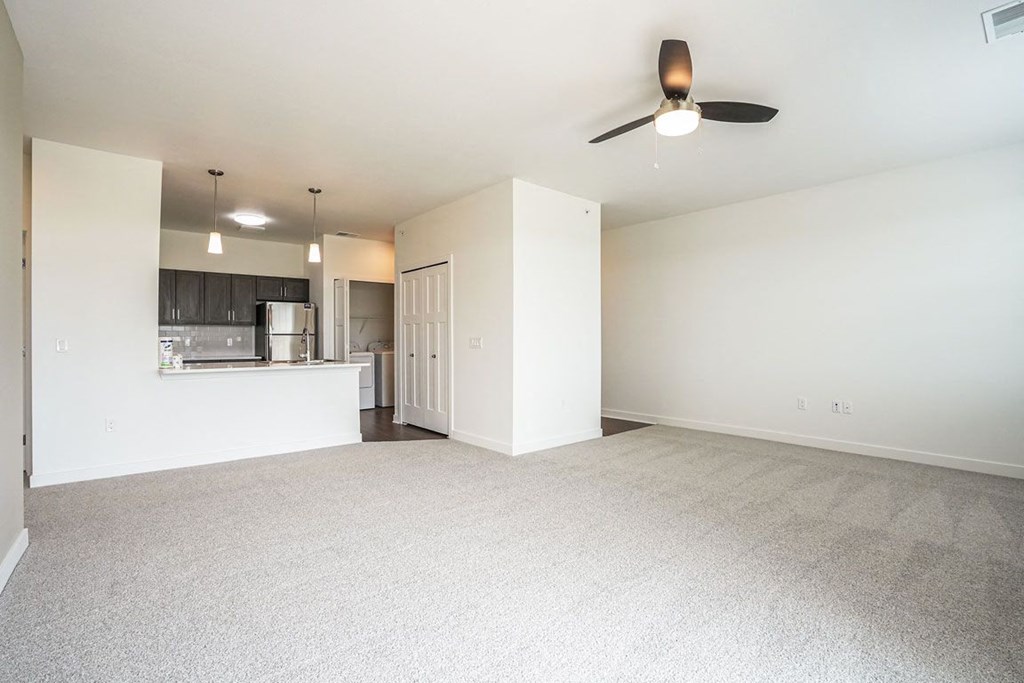 an empty living room with a ceiling fan and a kitchen in the background at Meadowbrooke Apartment Homes, Grand Rapids, 49512