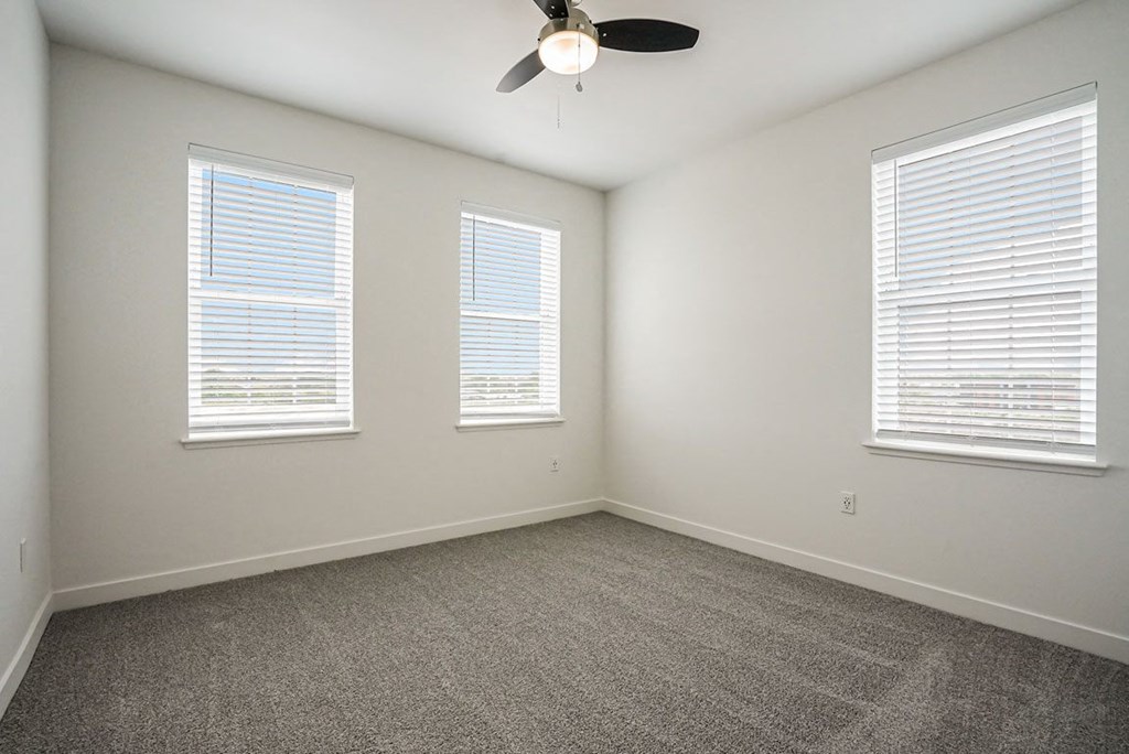 a bedroom with three windows and a ceiling fan at Meadowbrooke Apartment Homes, Grand Rapids, Michigan