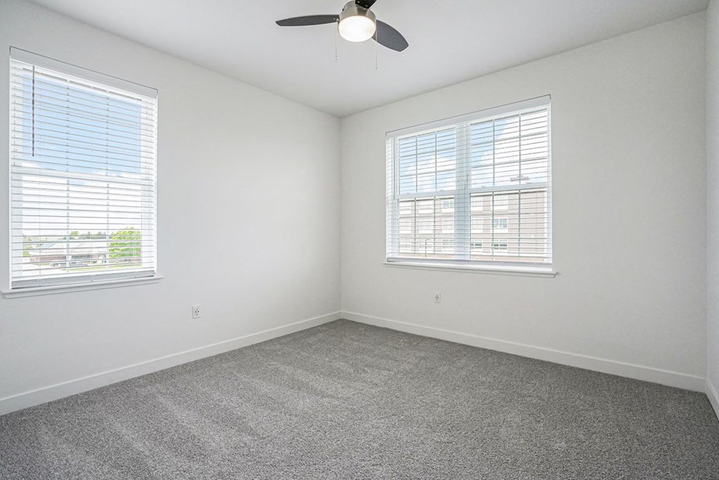 a bedroom with two windows and a ceiling fan at Meadowbrooke Apartment Homes, Michigan