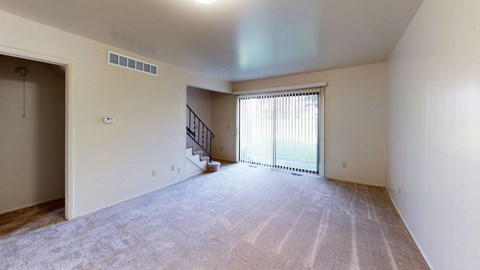 the living room and dining room of an empty house with a large window