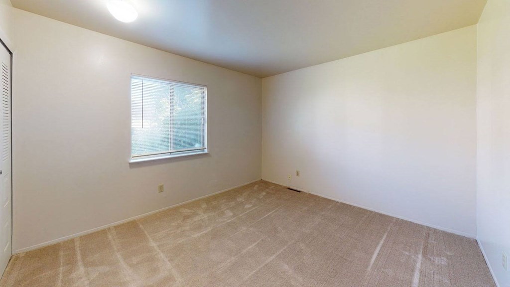 Spacious bedroom with a window and carpeting at Mount Royal Townhomes, Kalamazoo