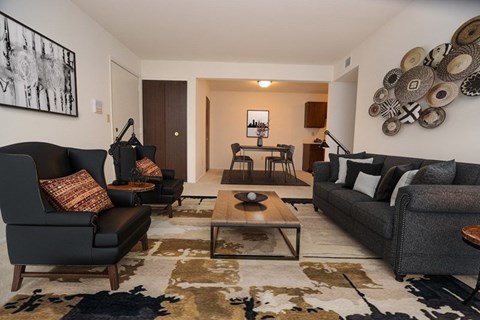 A living room with a black leather couch and a coffee table.