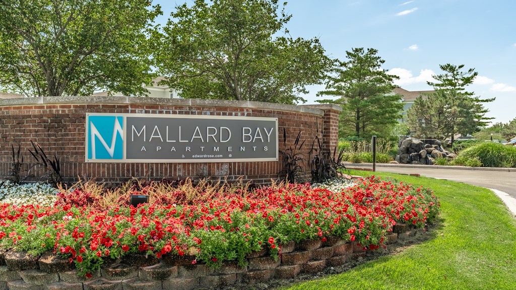 A sign for Mallard Bay Apartments is surrounded by flowers at Mallard Bay Apartments, Crown Point, Indiana