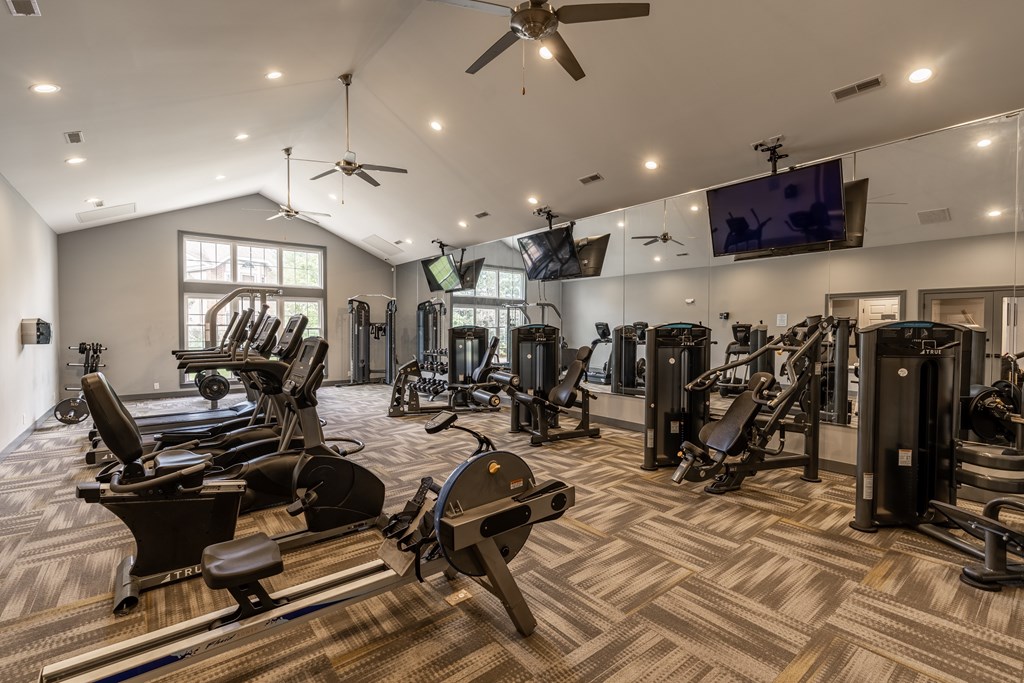 A spacious gym with a variety of equipment including treadmills, stationary bikes, and weight machines at Mallard Bay Apartments, Crown Point, Indiana
