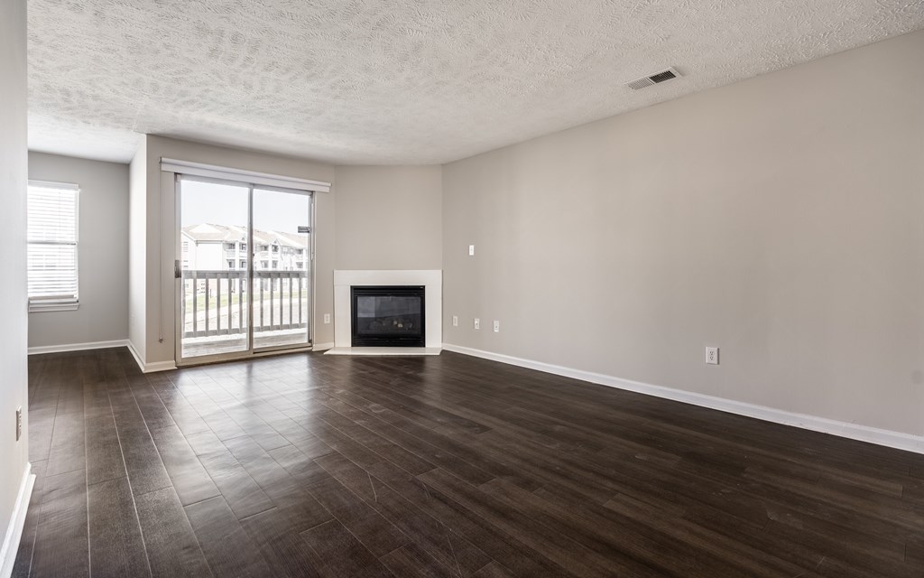 A spacious living room with a fireplace and sliding glass doors at Mallard Bay Apartments, Crown Point, Indiana