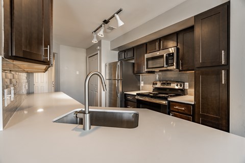 A modern kitchen with dark brown cabinets and a white countertop.