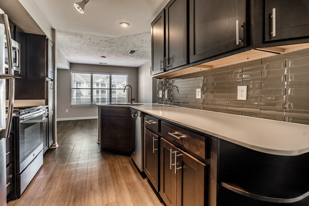 A modern kitchen with dark wood cabinets and stainless steel appliances at Mallard Bay Apartments, Crown Point, Indiana