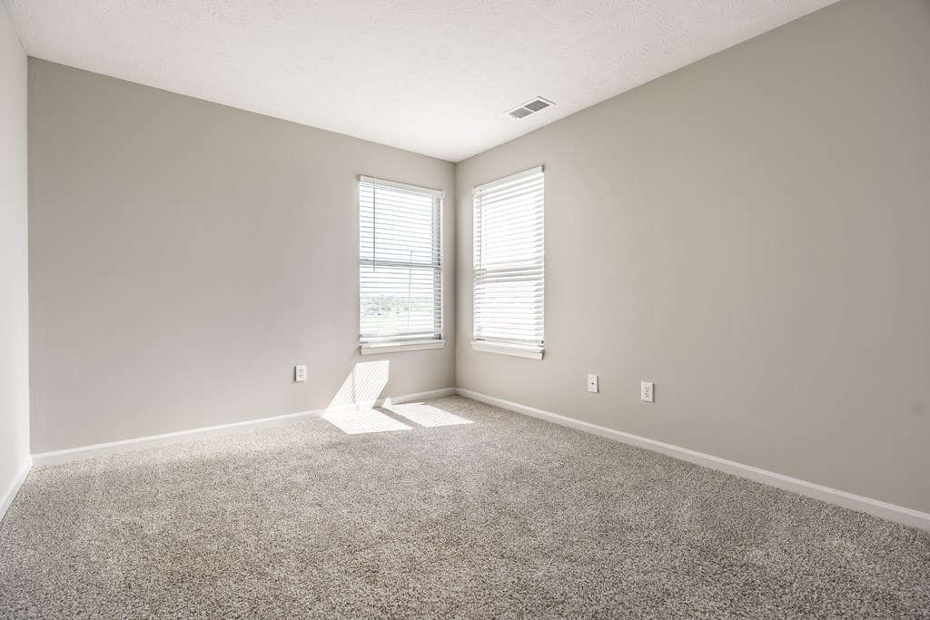 A room with a carpet floor and a window with blinds at Mallard Bay Apartments, Crown Point, Indiana