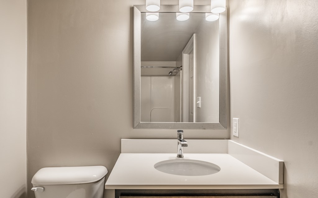 A bathroom with a toilet, sink and mirror at Mallard Bay Apartments, Crown Point, Indiana