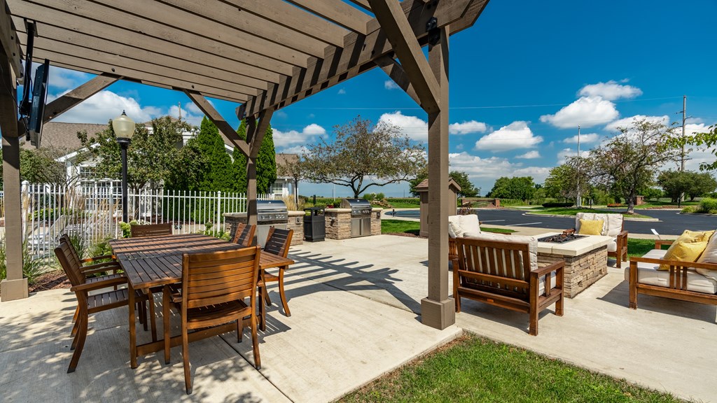 A wooden patio with a table and chairs under a pergola at Mallard Bay Apartments, Crown Point, Indiana
