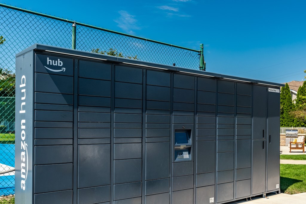 A large Amazon hub building is shown with a fence in the background at Mallard Bay Apartments, Crown Point, Indiana