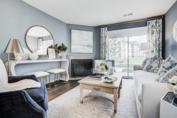 A living room with a grey couch, a wooden coffee table, and a fireplace at Mallard Bay Apartments, Crown Point, IN, 46307