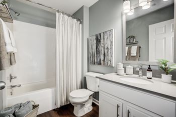 A white toilet is in a bathroom with a white tub and sink at Mallard Bay Apartments, Crown Point, IN