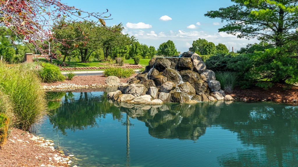A pond with rocks in the middle  at Mallard Bay Apartments, Crown Point, Indianaand trees in the background