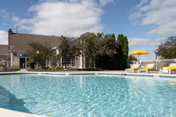 A swimming pool in front of a house with a yellow umbrella at Mallard Bay Apartments, Indiana