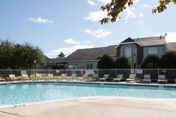 A pool surrounded by chairs and a building in the background at Mallard Bay Apartments, Indiana, 46307