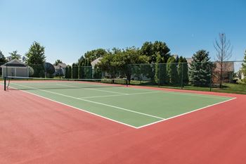 A tennis court with a net and trees in the background at Mallard Bay Apartments, Indiana, 46307
