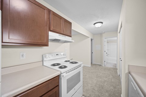 A kitchen with a white stove top oven and wooden cabinets.