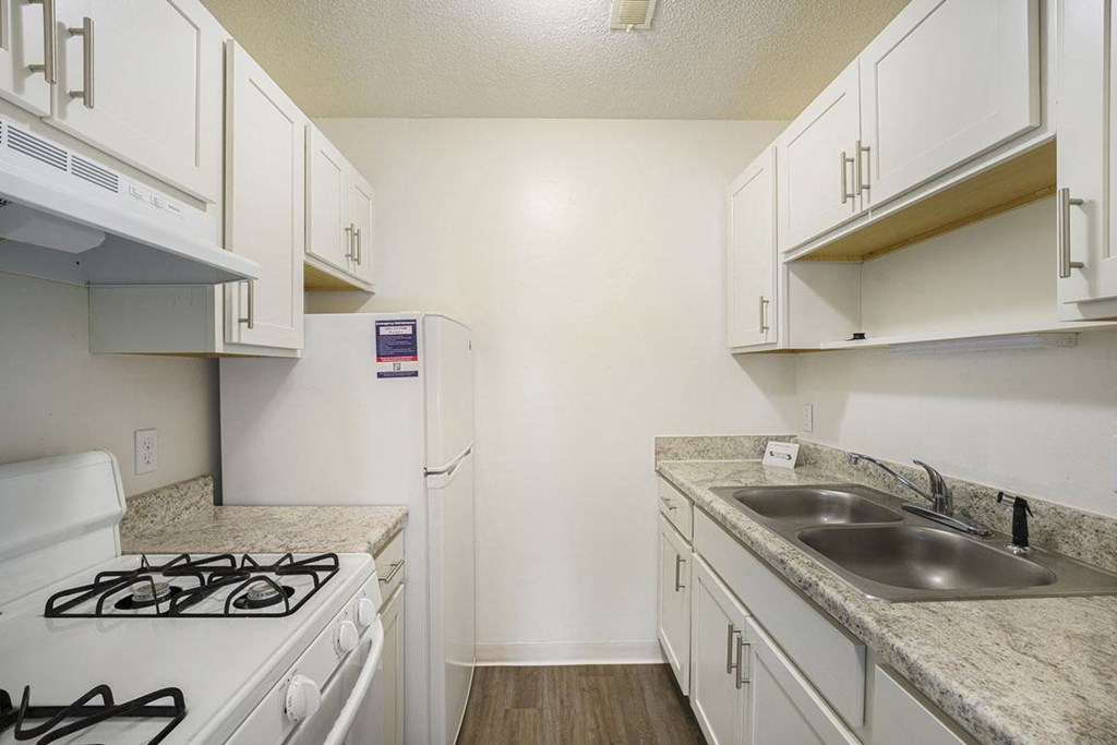 a kitchen with white cabinets and appliances at Newport Village Apartments, Portage, MI